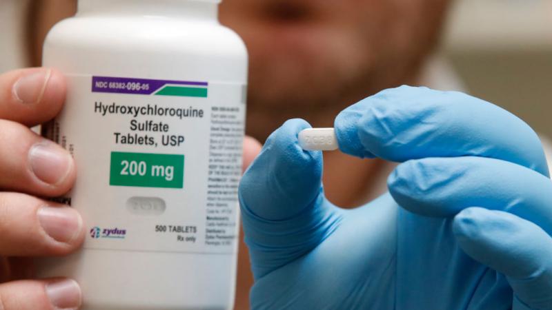 Pharmacy tech holding bottle and pill of hydroxychloroquine in Utah in May 2020