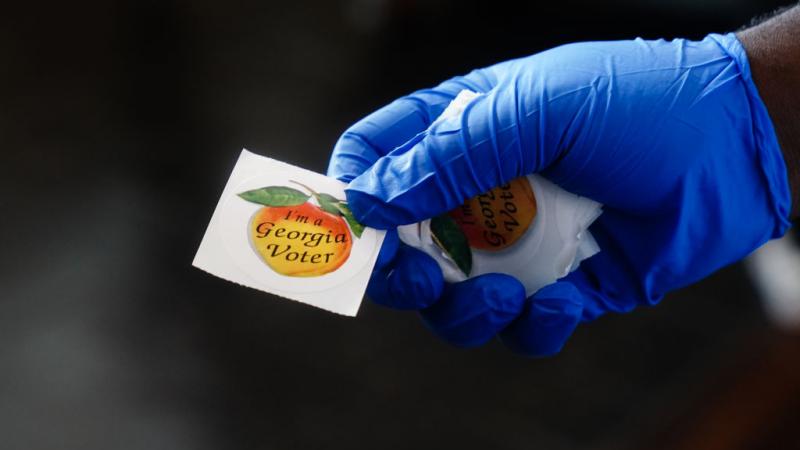 Polling place worker holding sticker in Georgia in June 2020