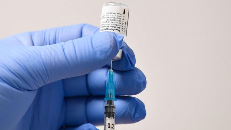 Person with needle and phial of Pfizer-BioNTech Covid-19 vaccine in Britain in December 2020