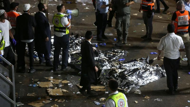 Ultra-Orthodox Jewish men next to covered bodies in Meron, Israel