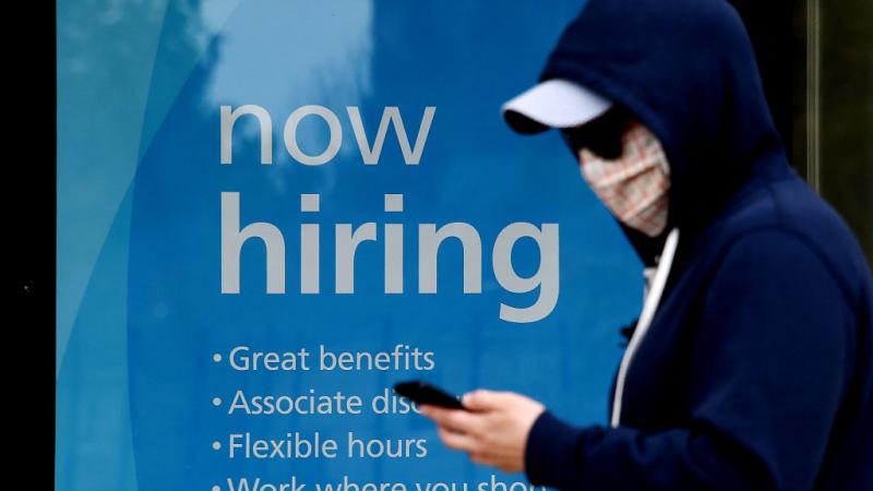 Person walks past now hiring sign in Virginia in May 2020