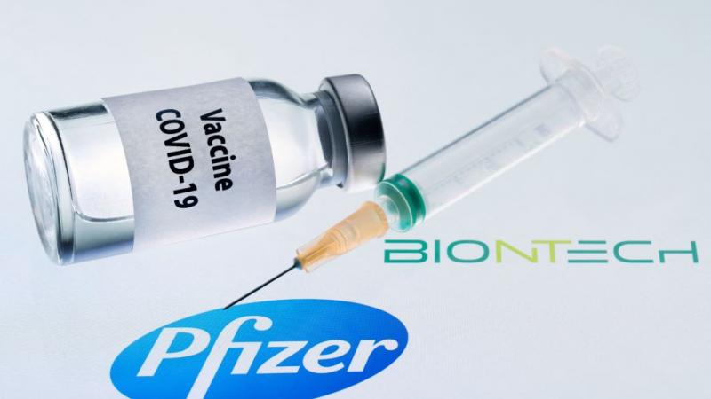 Illustration picture of a bottle and syringe next to Pfizer and Biontech logos