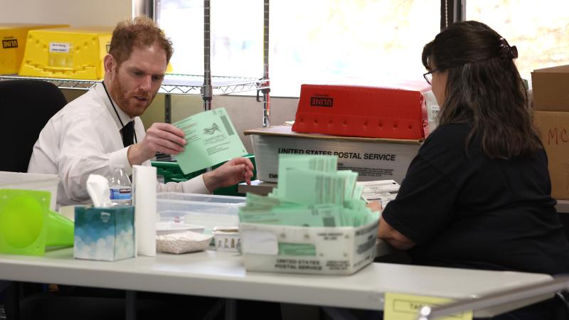 Maricopa County recorder Stephen Richer (L) opens mail in ballots at the Maricopa County Tabulation and Election Center on November 11, 2022 in Phoenix, Arizona.