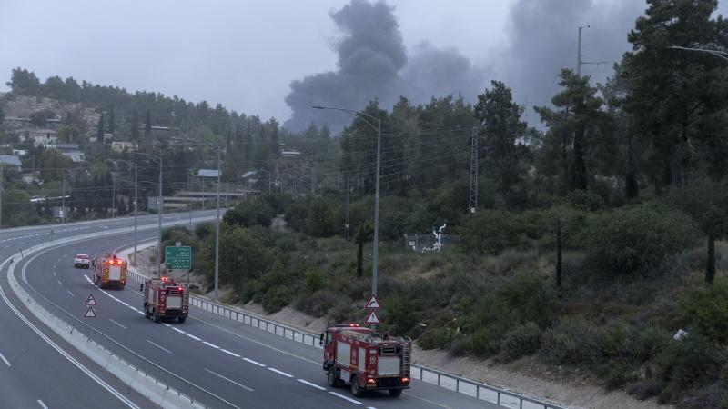 Fire trucks move along a main highway as smoke rises from a wildfire at the distance on April 30, 2025 in Jerusalem. 
