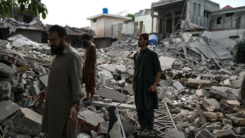 Locals stand on the debris of destroyed structures at the Government Health and Educational complex in Muridke about 30 kilometres from Lahore, on May 7, 2025, after Indian strikes.
