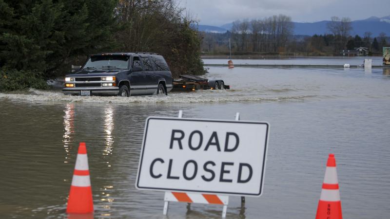 A driver manages to drive through flood waters from the Snohomish River in Snohomish, Washington, on December 11, 2025.