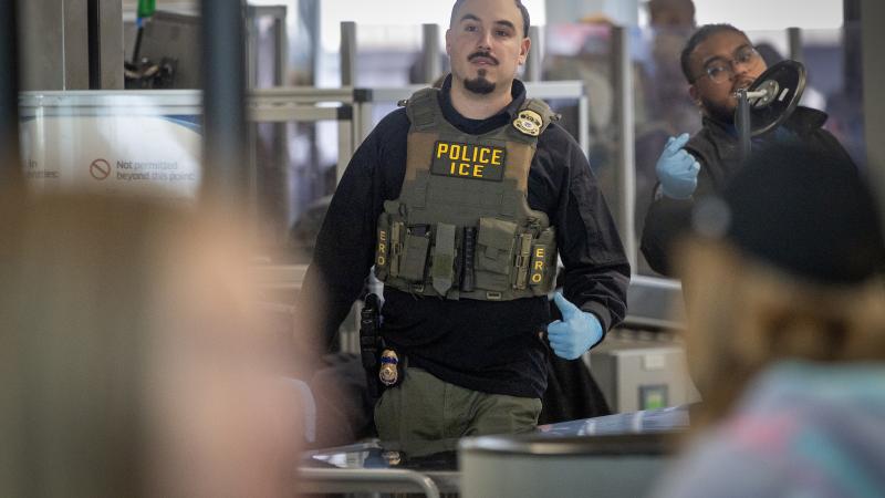 An ICE agent assists TSA in screening passengers at a security checkpoint at O'Hare International Airport on March 27 in Chicago, Illinois.