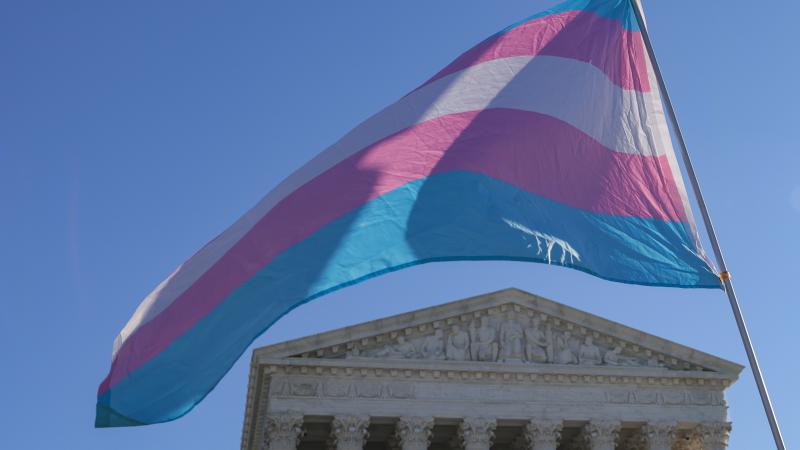 Protesters supporting transgender athletes competing in women's sports wave a transgender pride flag outside the Supreme Court on Jan. 13, 2026 in Washington, D.C.