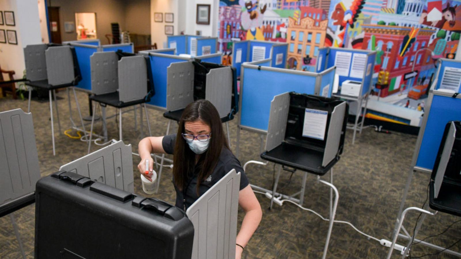 A poll worker sanitizes voting booths in Denver, Colorado, June 30