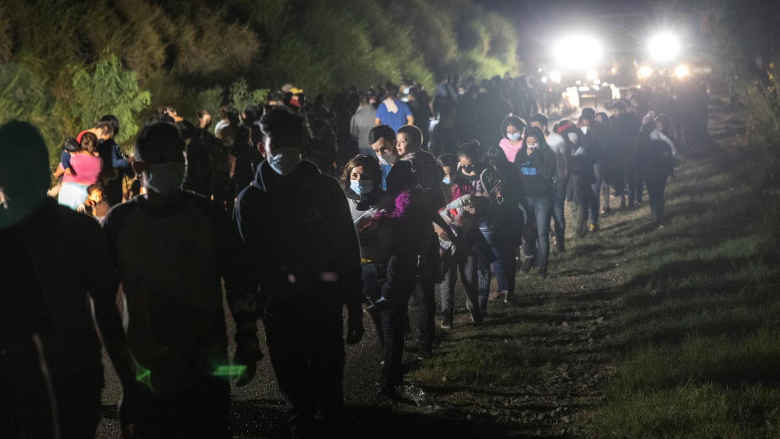 Immigrants walk towards transport busses to a processing center from a U.S. Border Patrol checkpoint on August 14, 2021 in Roma, Texas.